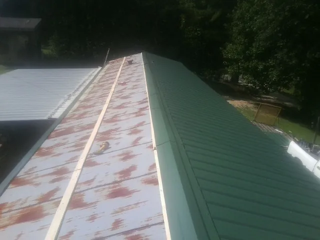 Old rusted panels beside newly installed green metal roofing — Wind Damage Roof Repair by Roofing Brothers in Estill Springs