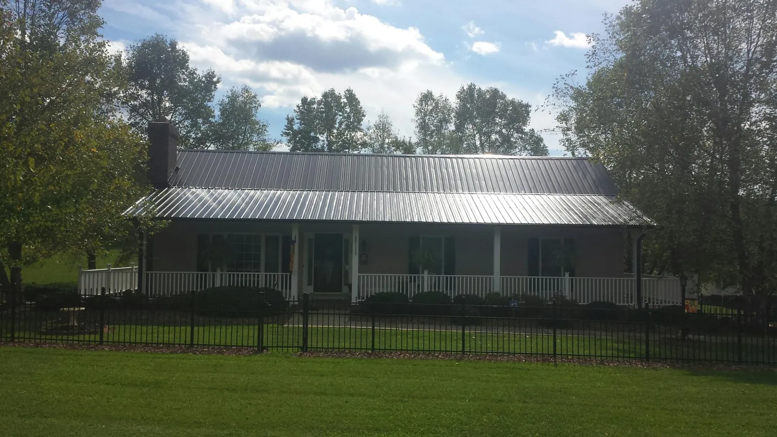 Gray metal roof on a brick ranch with a full width front porch — Gutter Guard Installation work by our crew in Estill Springs