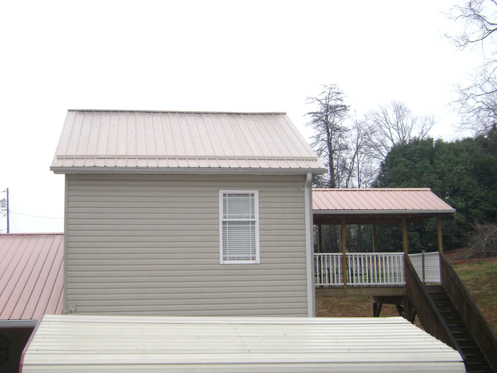 Tan metal roofs on a two story addition and attached porch, from a Roof Replacement job in Estill Springs