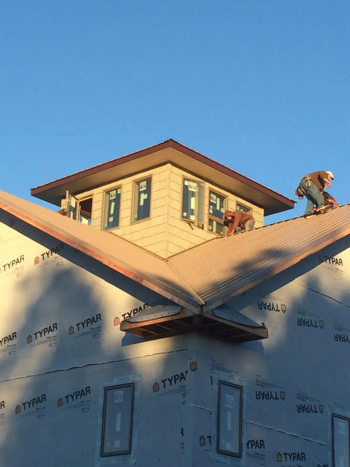 Roofers working around a rooftop cupola on a new metal roof at sunset — Roof Waterproofing in Estill Springs by Roofing Brothers